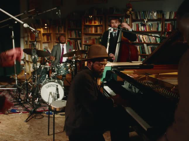 A cool jazz trio plays for a dancing audience during an intimate live performance in a book-lined room