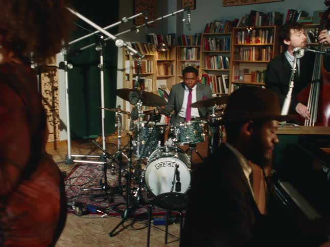 A couple slow dances intimately as the camera pans to reveal a jazz trio performing in a cozy studio