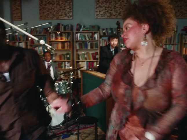 A couple loses themselves in a soulful dance as a live jazz band plays in a cozy, book-lined studio