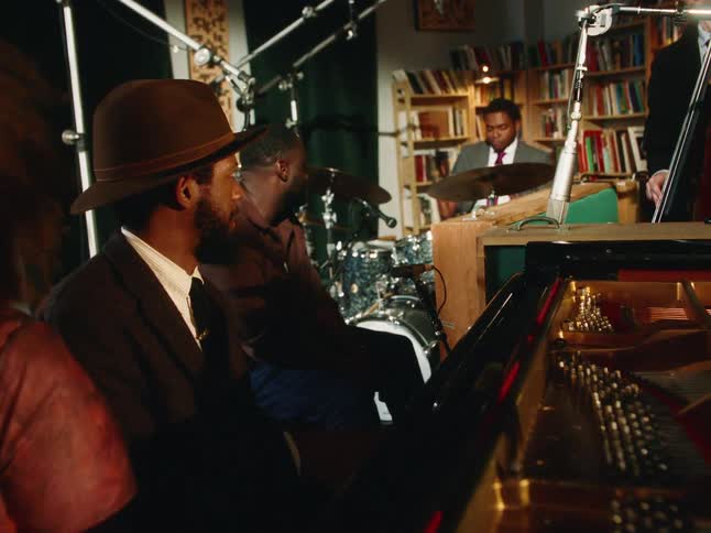 A diverse jazz quartet, including a singer and pianist, passionately performs in a cozy, book-lined music studio