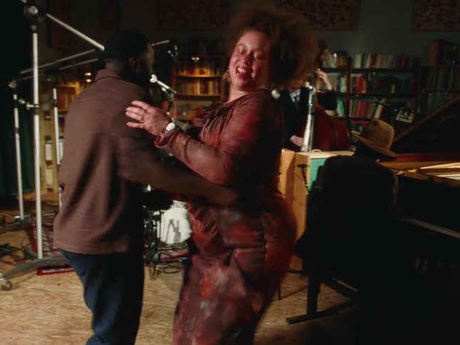 A lively couple joyfully swing dances to a live jazz band performing in an intimate, book-lined studio