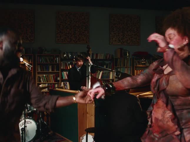 An energetic couple dances in slow motion to the rhythm of a live jazz band performing in a cozy studio