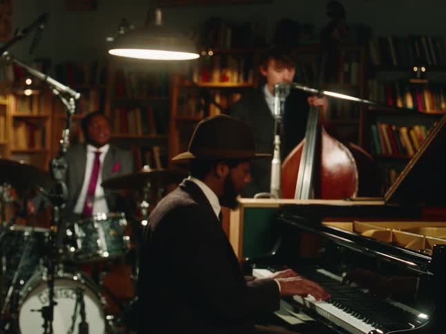 A stylish jazz trio performs in a cozy, dimly-lit room with a piano, upright bass, and drums