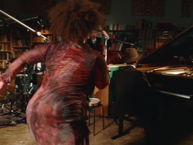 A couple joyfully swing dances with exuberant energy while a jazz band performs live in a cozy, book-lined studio