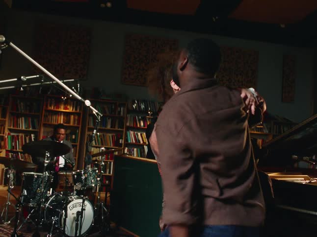 A couple shares an intimate slow dance in a music studio as a jazz band plays in the background