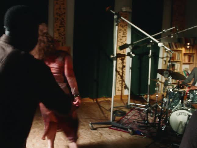 A man and woman dance with soulful energy to a live jazz band performing in a cozy studio