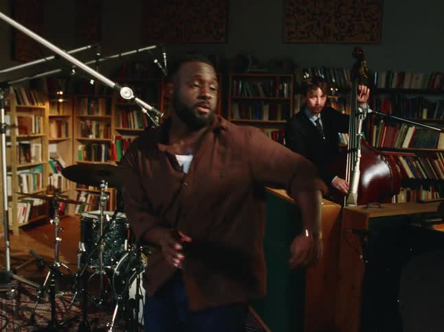 A soulful singer dances with abandon as his jazz band performs in an intimate, book-lined recording studio
