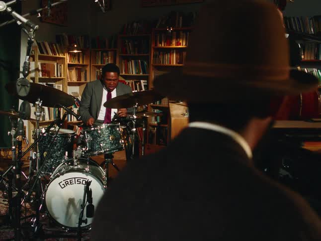 A soulful jazz band performs in an intimate, book-lined studio, with the camera slowly revealing each member