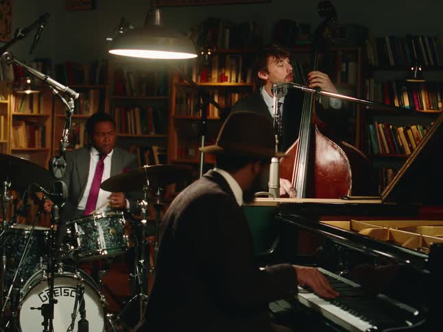 A stylish jazz trio passionately performs in a dimly lit library during an intimate recording session