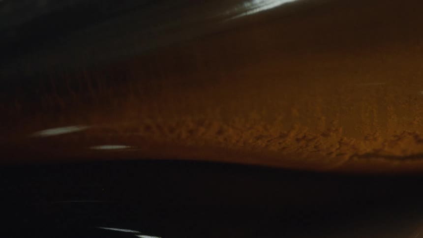 Macro close up of dark amber liquid with yeast and sediment swirling during the fermentation process