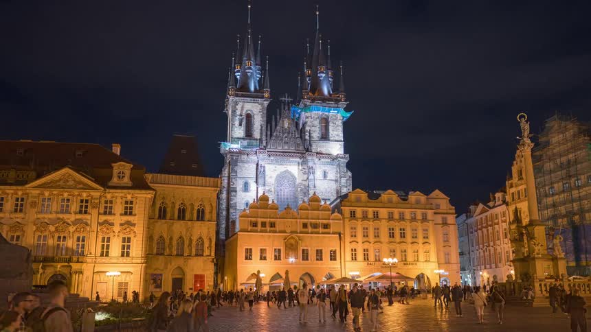 Hyperlapse reveals the bustling Old Town Square in Prague, Czech Republic at night, with the illuminated Church of Our Lady before Týn standing majestically