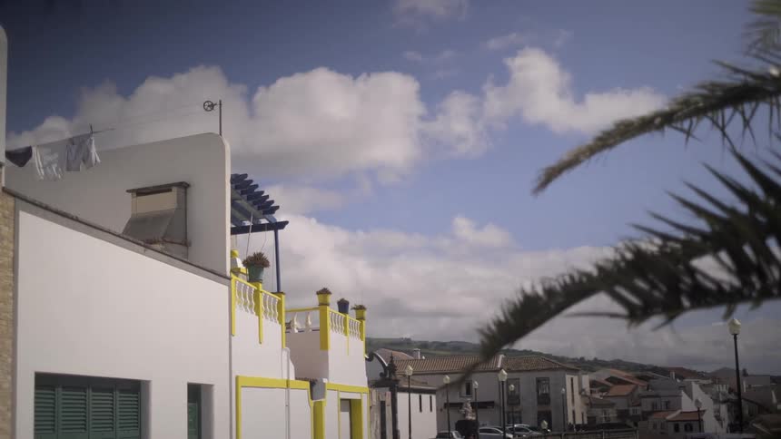 A calm street in a picturesque town with white buildings and laundry drying under a cloudy blue sky