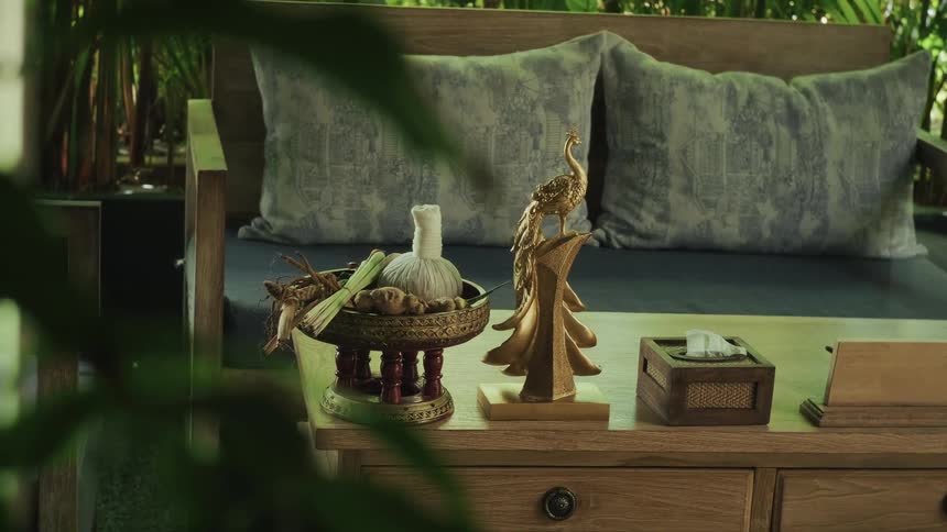 A still shot of a traditional Thai herbal massage ball and aromatic ingredients on a wooden table in a tranquil spa setting