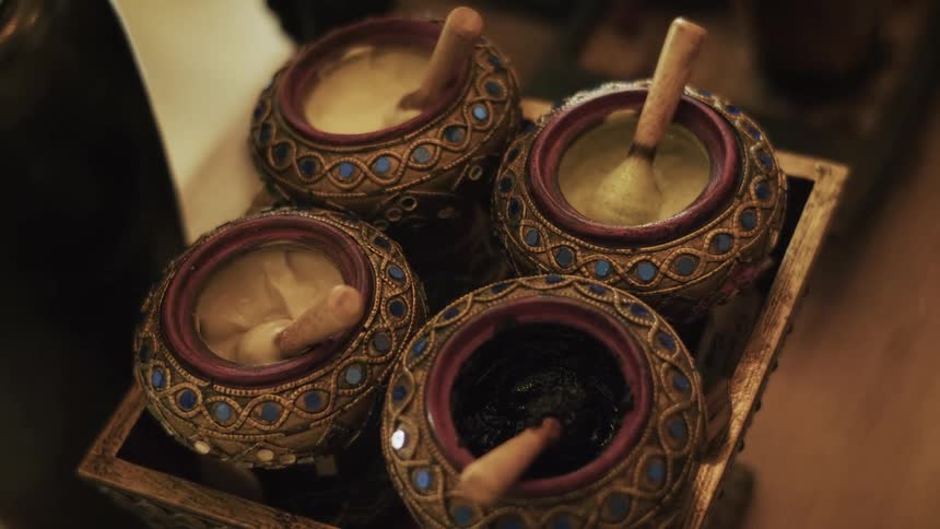 An assortment of colorful, natural spa treatments are displayed in ornate, traditional Thai-style containers