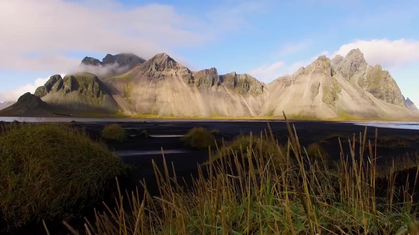 low flight over grass hills, with epic mountain range in distance