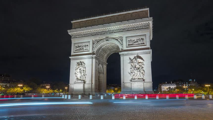 A mesmerizing night timelapse captures streaks of traffic lights flowing around the iconic Arc de Triomphe in Paris, France