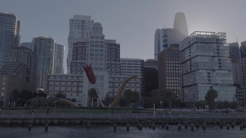 Tracking shot from the bay reveals San Francisco's sunny downtown skyline, featuring the Embarcadero and the iconic Cupid's Span sculpture