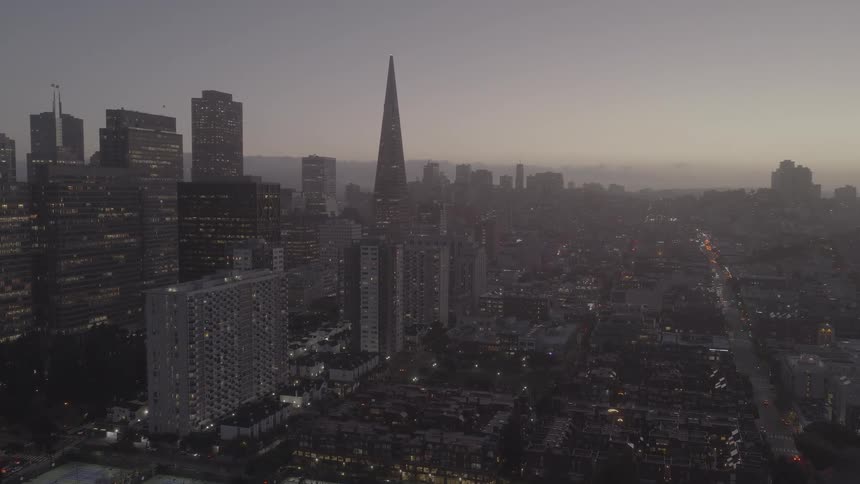 A slow, sweeping aerial shot reveals the iconic San Francisco skyline at dusk, panning from the financial district to the Ferry Building and Telegraph Hill