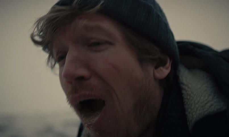 Extreme close-up of a hiker spitting snow from his mouth in slow motion during a fierce blizzard