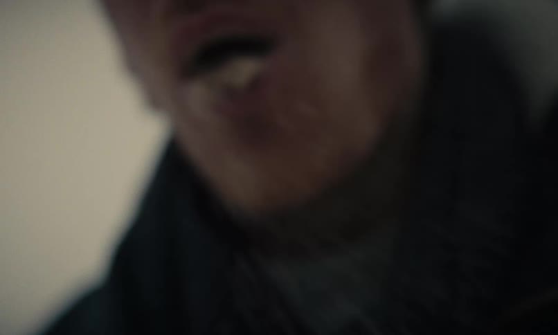 Extreme close-up of a bearded man's mouth as he spits out a cloud of snow in super slow motion