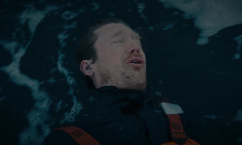 Close up of an unconscious man floating in the rough sea as a powerful wave washes over him in slow motion