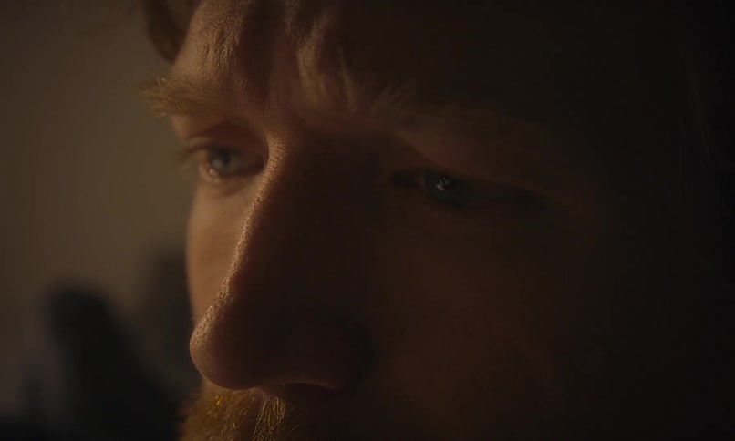 Extreme close-up on the sad, concerned eyes of a bearded man in a dimly lit, moody room