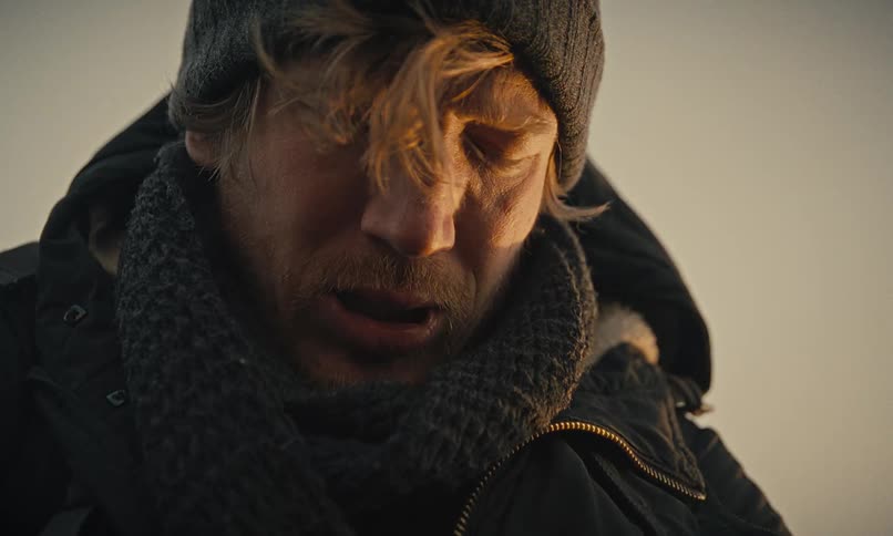 A close-up shot of a tired man in winter clothing, struggling with physical labor in the cold
