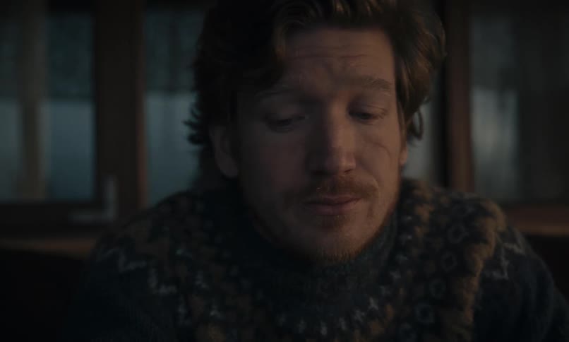 Intimate close-up portrait of a thoughtful man in a cozy sweater looking on with a gentle and melancholic expression
