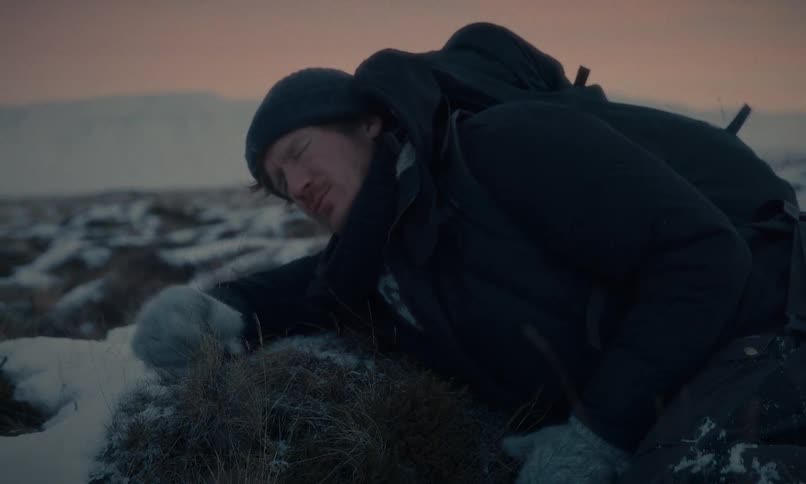 A weary hiker collapses from exhaustion in a snowy, remote landscape during a cold twilight