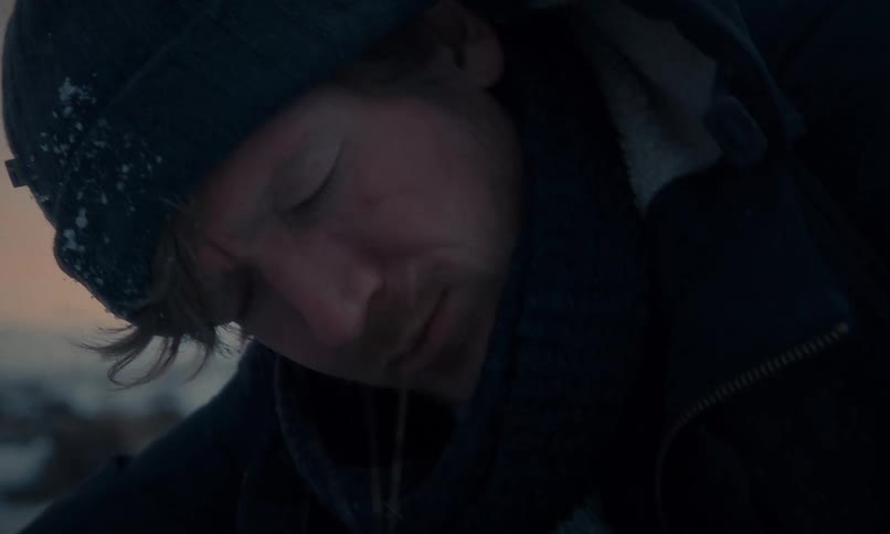 A desperate and exhausted man with a scar on his face collapses in the freezing snow in slow motion