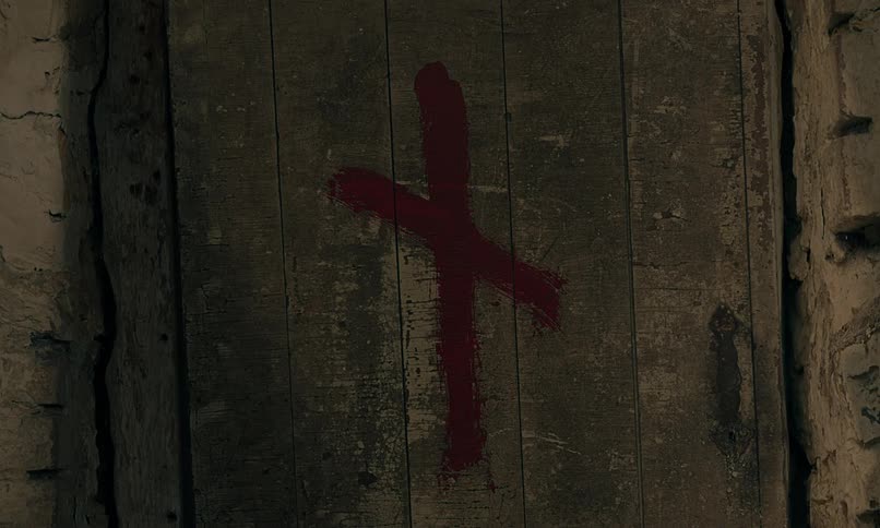 Ominous red cross painted on a dark medieval wooden door to signify the plague