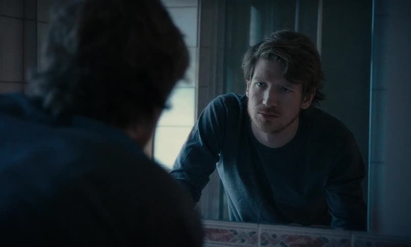 An anxious man has an intense moment of self-reflection while looking in the bathroom mirror
