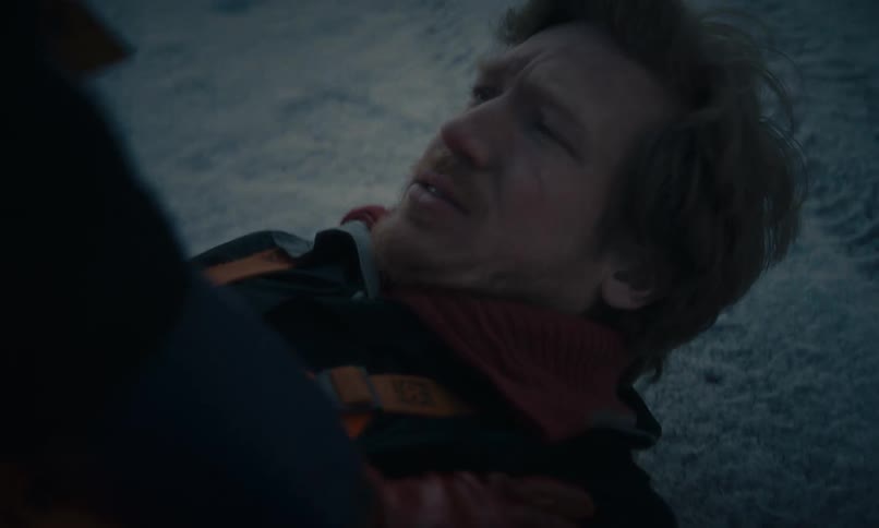 A distressed man lies injured in the snow, gasping for air while being shaken by an unseen person