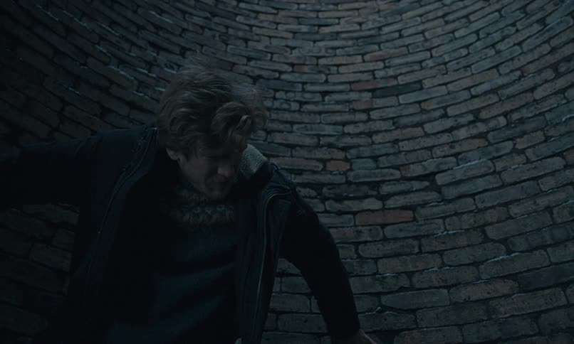 A terrified man wakes up at the bottom of a dark, circular brick well and screams in horror as he realizes he is trapped