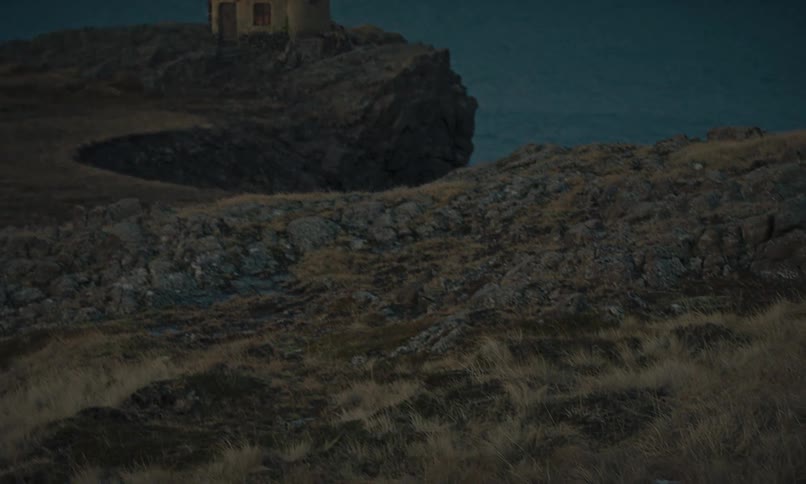 A solitary lighthouse on a rocky coast illuminates at dusk as a tired hiker treks through the desolate landscape