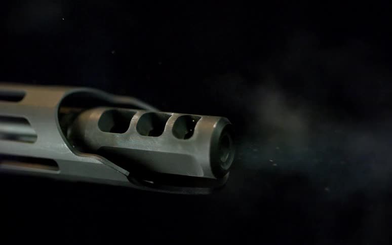 A super slow-motion close-up of a rifle firing a bullet, with visible smoke and muzzle flash against a black background