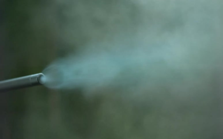 A close-up, super slow-motion shot of a rifle firing, capturing the bullet's exit, the muzzle flash, and the resulting smoke