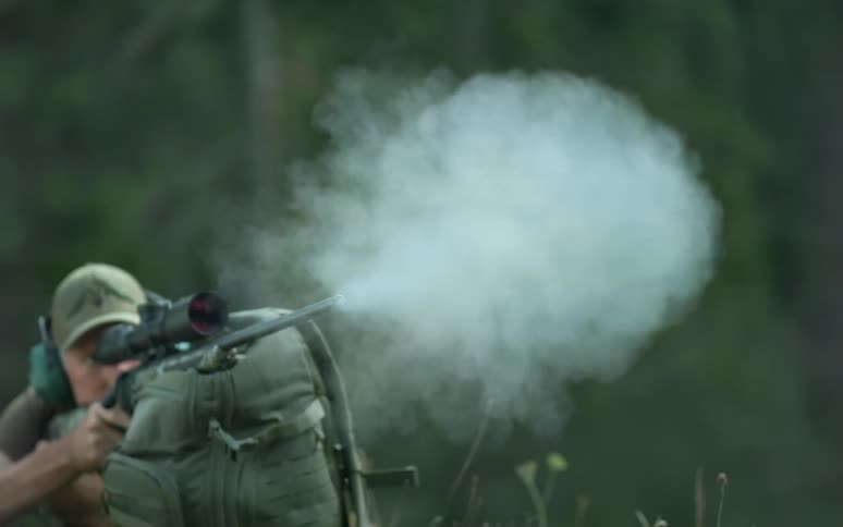 Super slow motion close-up of a rifle firing, showing the bullet, muzzle flash, and smoke cloud expanding from the barrel