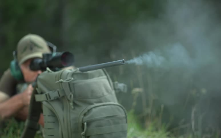 A sniper rifle fires a bullet, shown in an extreme slow-motion close-up of the muzzle flash and smoke
