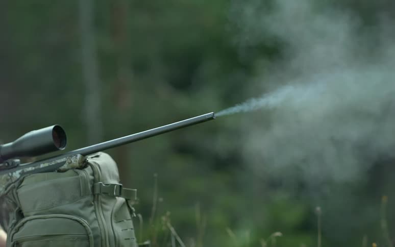 Super slow-motion close-up of a rifle barrel firing a bullet with a fiery muzzle flash and smoke