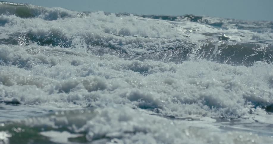 Dramatic slow-motion close-up of a turbulent ocean wave crashing and churning into white seafoam