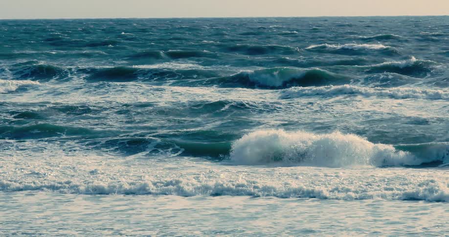 Deep blue ocean waves roll and crash in a powerful slow-motion display
