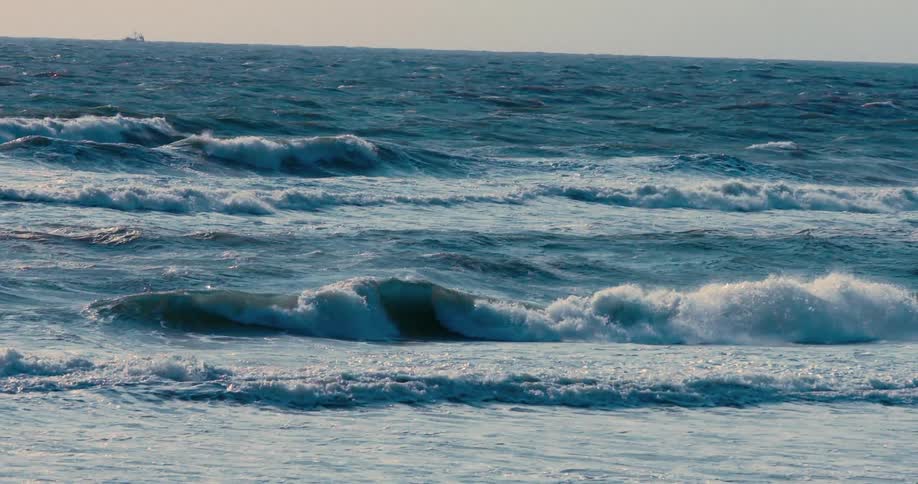 Slow motion captures the powerful and mesmerizing rhythm of deep blue ocean waves rolling endlessly towards the shore