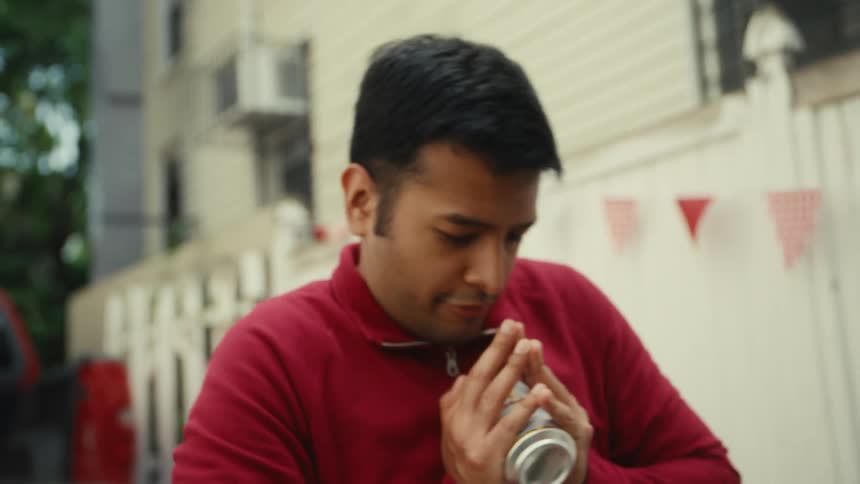 A man grabs a cold can of beer from an ice-filled cooler during a casual backyard gathering