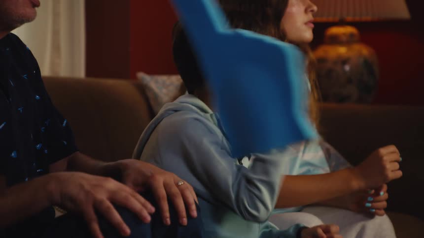A young sports fan with face paint is visibly upset after his team loses while watching the game on TV with his family