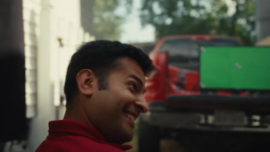Two male friends have a conversation before sitting down to watch a green screen TV propped up in the back of a pickup truck