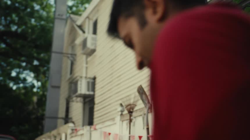 A young girl in a red soccer jersey happily throws a ball to a man who juggles it with his feet during a backyard party in slow motion