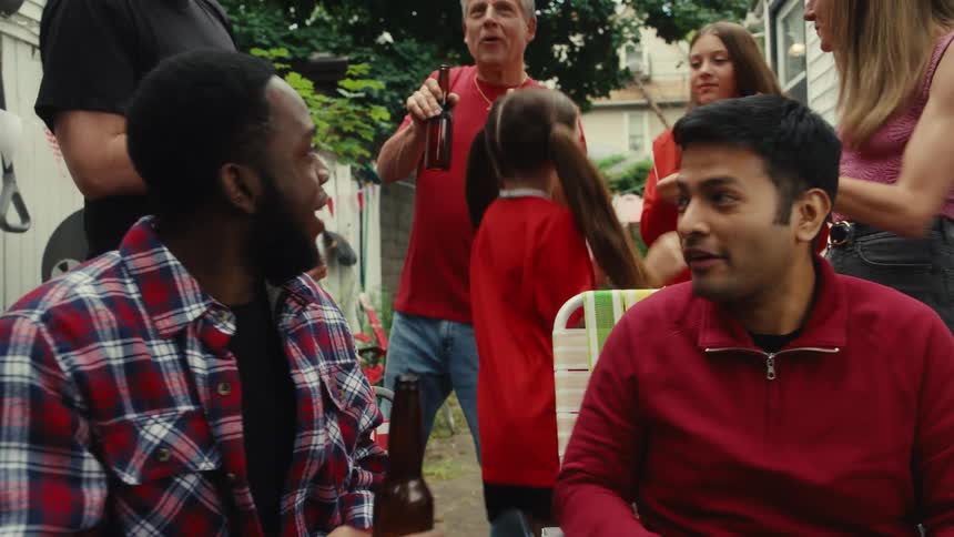 A diverse group of friends and family laugh, dance, and celebrate at a backyard barbecue party in slow motion