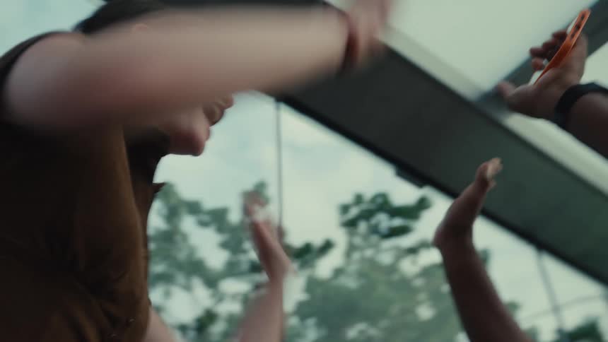 Friends react with shock and then explode into joyful celebration while watching a thrilling event on a smartphone in slow motion
