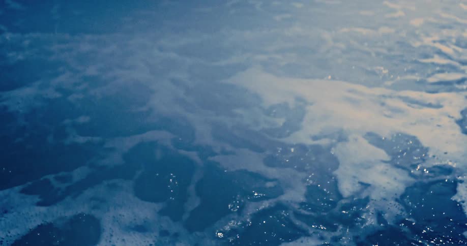 A tranquil close-up of dark blue water churning with foam in slow motion